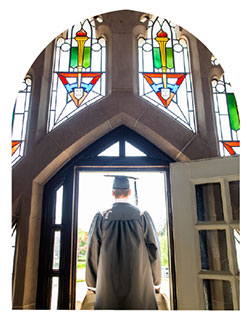 A student stands looking out from the balcony of Harkins hall